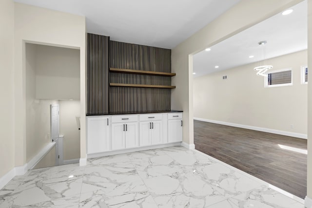 unfurnished living room with recessed lighting, marble finish floor, baseboards, and a notable chandelier