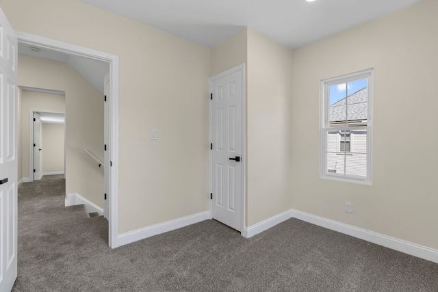 spare room featuring baseboards and dark colored carpet