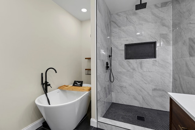 full bathroom with baseboards, a freestanding bath, a tile shower, and vanity