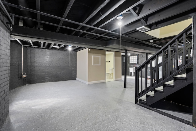 basement with visible vents, brick wall, and stairway
