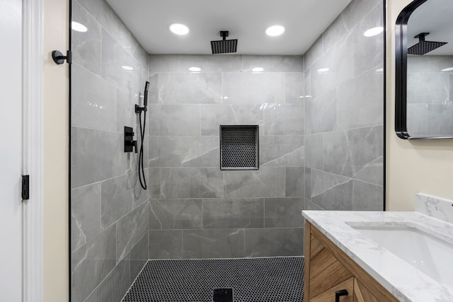 full bathroom featuring recessed lighting, a tile shower, and vanity