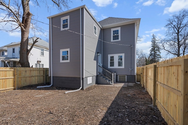 back of property with entry steps and a fenced backyard