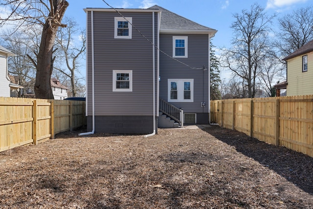 rear view of house with roof with shingles, a fenced backyard, and entry steps