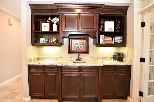 bar featuring indoor wet bar, baseboards, ornamental molding, and a sink
