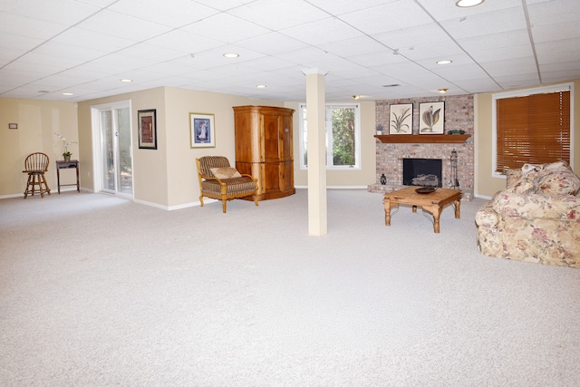 living area with baseboards, a drop ceiling, light carpet, and a fireplace