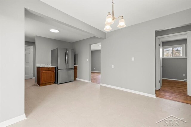 kitchen featuring pendant lighting, light countertops, baseboards, freestanding refrigerator, and a chandelier