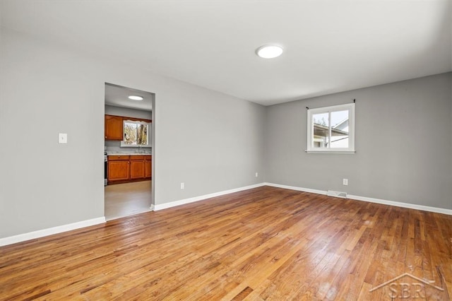 unfurnished room featuring baseboards, visible vents, and light wood-type flooring