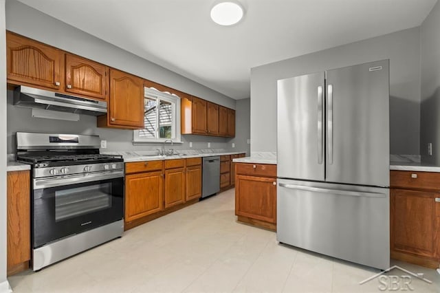kitchen featuring under cabinet range hood, stainless steel appliances, a sink, and light countertops