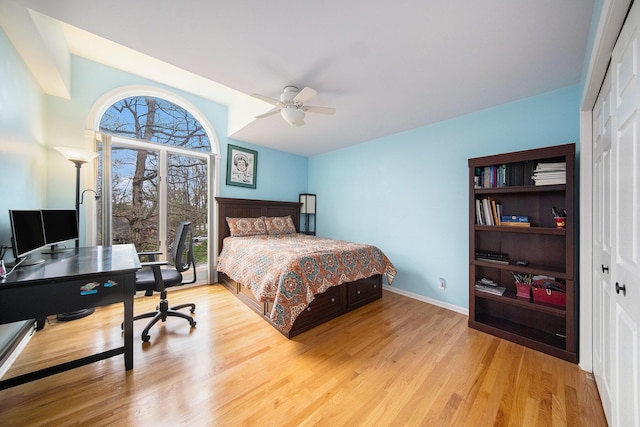 bedroom with a ceiling fan, wood finished floors, baseboards, a closet, and lofted ceiling
