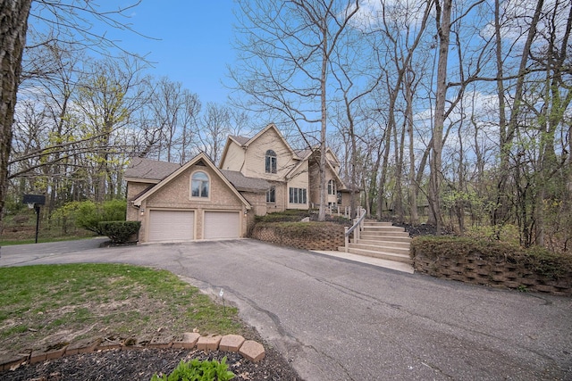 view of front of property with an attached garage, aphalt driveway, roof with shingles, and brick siding