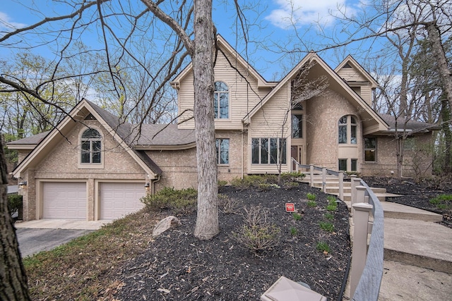 traditional home featuring brick siding, a garage, and aphalt driveway