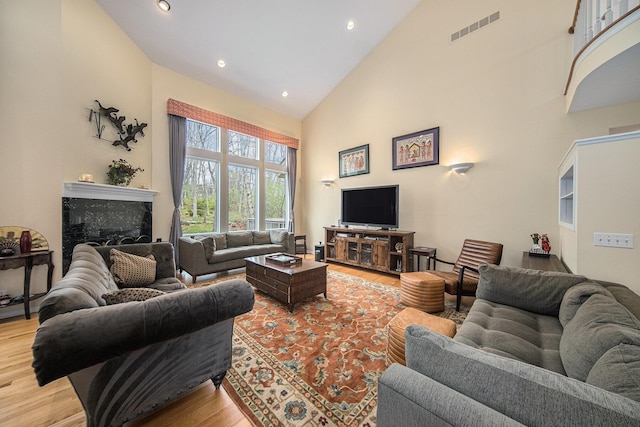 living room with light wood-style floors, high vaulted ceiling, recessed lighting, and visible vents