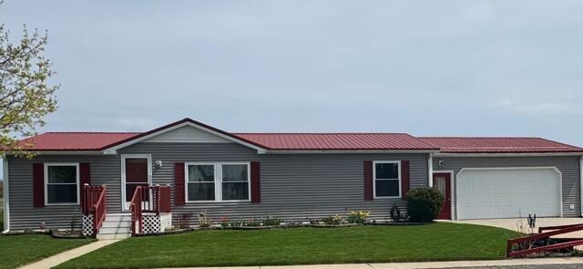 view of front of property featuring a garage, a front lawn, metal roof, and concrete driveway