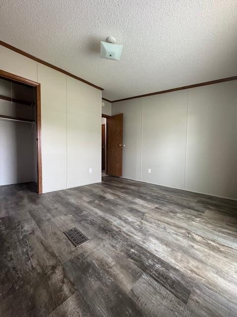 unfurnished bedroom with crown molding, a textured ceiling, visible vents, and wood finished floors