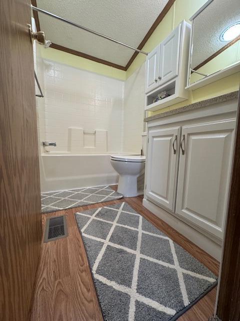 bathroom with visible vents, a textured ceiling, wood finished floors, and toilet