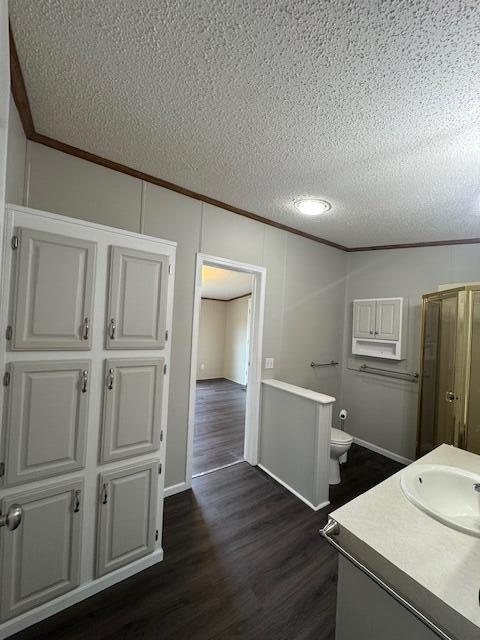 bathroom featuring crown molding, a textured ceiling, wood finished floors, and toilet