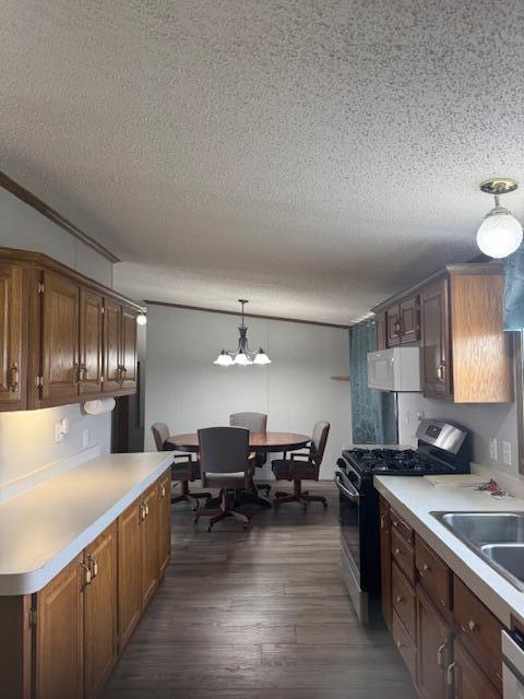 kitchen featuring a sink, light countertops, a textured ceiling, gas range, and white microwave