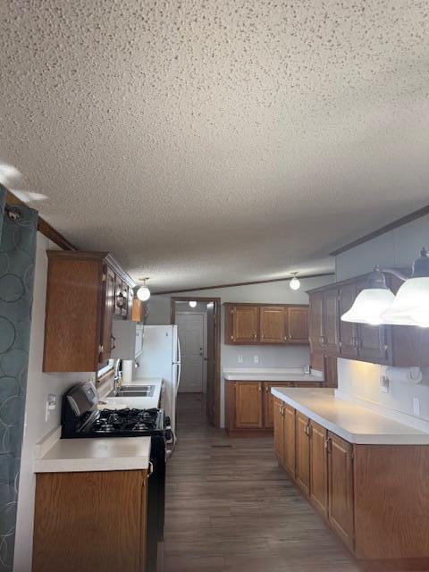 kitchen featuring light countertops, dark wood-style flooring, a textured ceiling, and gas stove