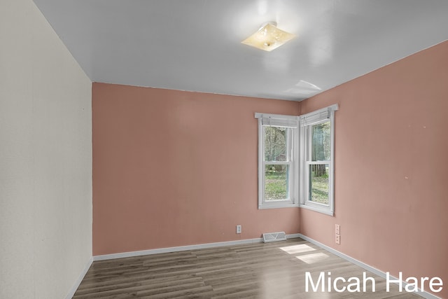 spare room featuring baseboards, wood finished floors, and visible vents