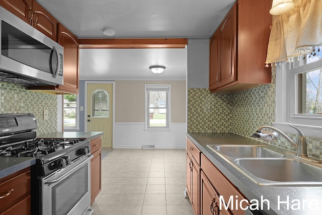 kitchen featuring visible vents, dark countertops, tasteful backsplash, a sink, and stainless steel appliances