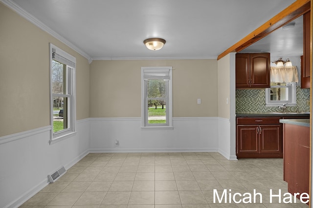 kitchen with decorative backsplash, visible vents, a sink, reddish brown cabinets, and ornamental molding
