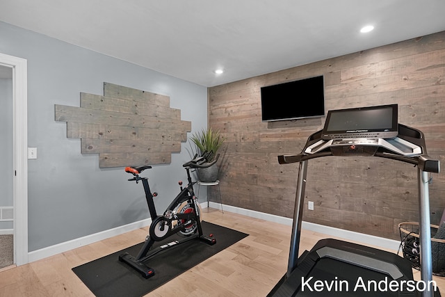 exercise area featuring recessed lighting, wood walls, baseboards, and wood finished floors
