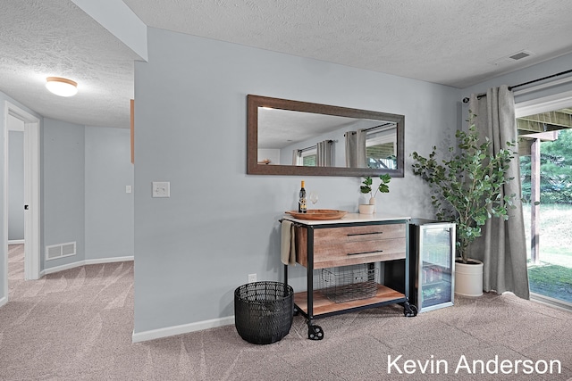 corridor featuring carpet floors, a textured ceiling, baseboards, and visible vents