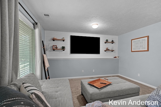 carpeted living room with a healthy amount of sunlight, baseboards, a textured ceiling, and visible vents