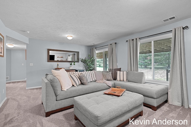 living area with a textured ceiling, visible vents, light carpet, and baseboards