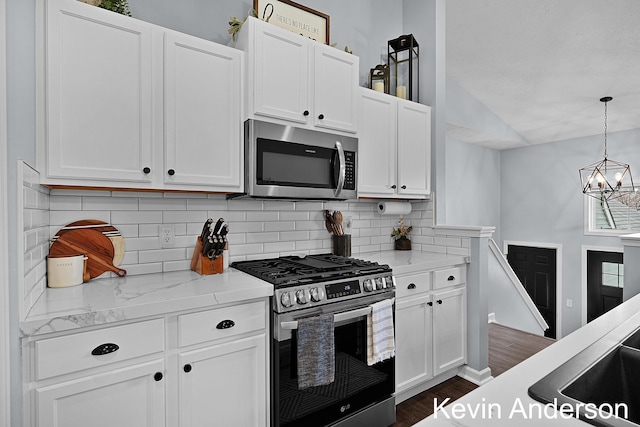 kitchen featuring backsplash, stainless steel appliances, white cabinets, and a notable chandelier