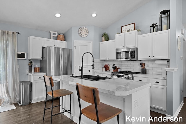 kitchen featuring stainless steel appliances, decorative backsplash, a sink, and white cabinetry