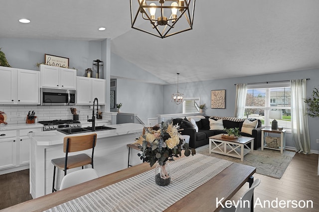 dining room with recessed lighting, a chandelier, vaulted ceiling, and light wood-style floors