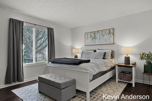 bedroom with a textured ceiling, baseboards, and wood finished floors
