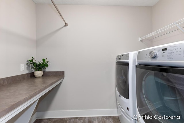laundry room featuring dark wood-style flooring, laundry area, washing machine and dryer, and baseboards