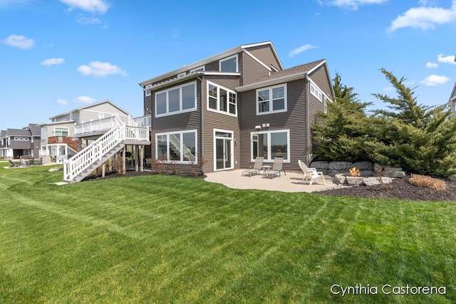rear view of house featuring stairs, an outdoor fire pit, a deck, a lawn, and a patio