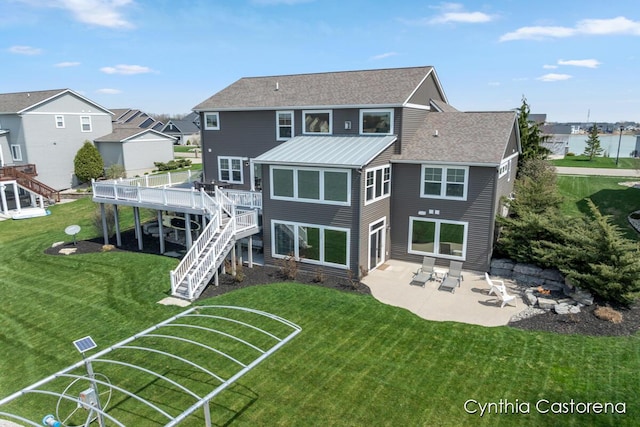 back of house featuring stairway, a standing seam roof, a deck with water view, and a patio area
