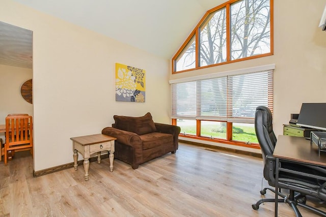 office space with high vaulted ceiling, plenty of natural light, baseboards, and light wood-style flooring