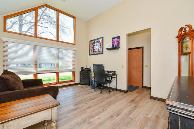 office featuring baseboards, high vaulted ceiling, and light wood-type flooring