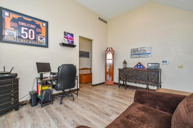office area with baseboards, lofted ceiling, wood finished floors, and visible vents