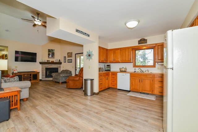 kitchen with a sink, light wood-style floors, white appliances, and a healthy amount of sunlight
