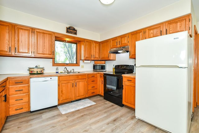 kitchen featuring a sink, light wood-style floors, white appliances, light countertops, and under cabinet range hood