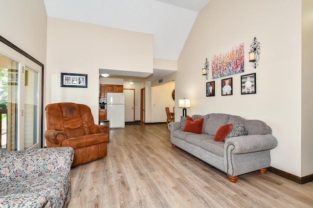 living area featuring baseboards, high vaulted ceiling, and light wood-style floors