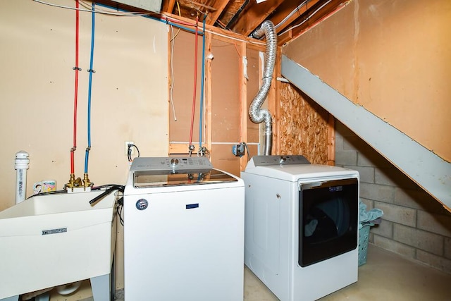 clothes washing area with a sink, concrete block wall, laundry area, and washer and dryer