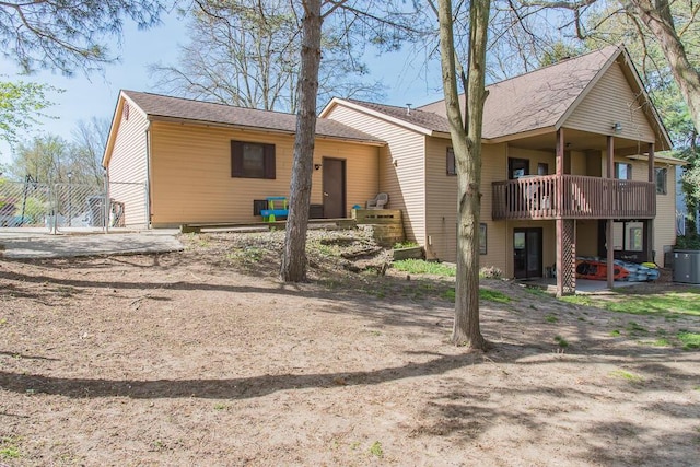 rear view of house featuring a wooden deck, a shingled roof, and central AC