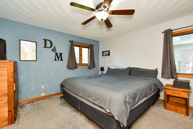 carpeted bedroom featuring a ceiling fan, baseboards, and multiple windows
