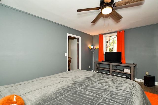 bedroom featuring baseboards, ceiling fan, visible vents, and wood finished floors