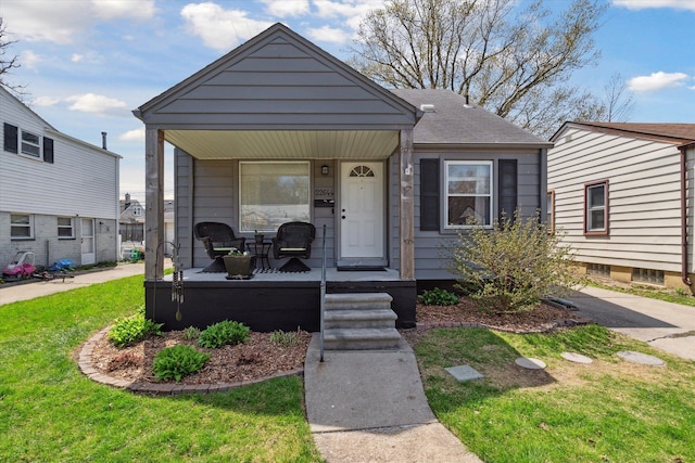 bungalow with a porch, a front lawn, and roof with shingles
