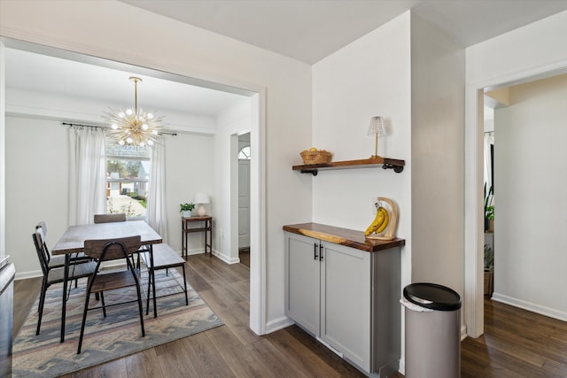 dining space with dark wood-type flooring, baseboards, and a notable chandelier
