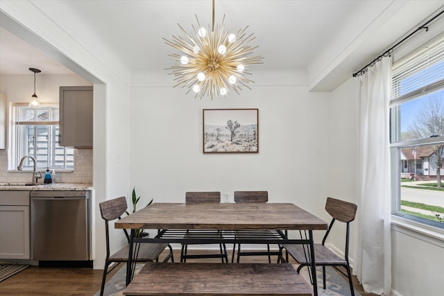 dining space featuring a notable chandelier, a wealth of natural light, and dark wood finished floors