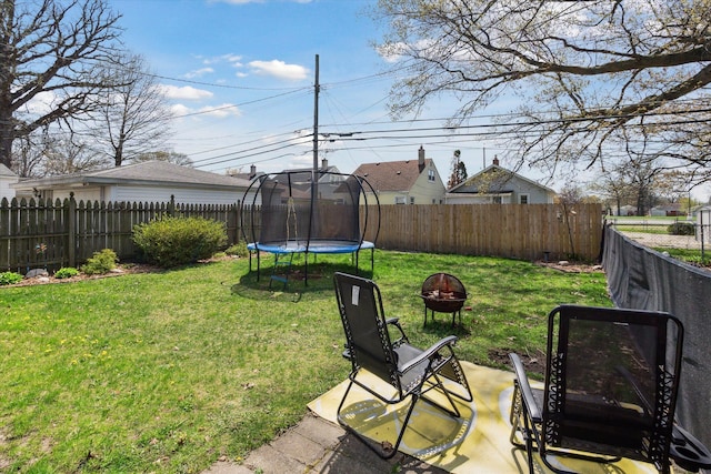 view of yard with a fire pit, a fenced backyard, and a trampoline